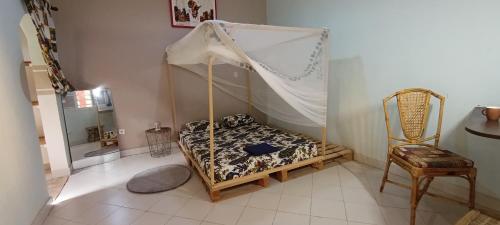 1 dormitorio con 1 cama con dosel y 1 silla en Zion, en Toubab Dialaw
