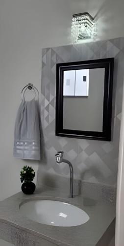 a bathroom sink with a mirror and a potted plant at Sobrado 4 amplo e confortável in Corumbá