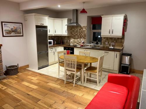 een keuken met een houten tafel en een rode bank bij Belmullet Town Holiday Home in Belmullet