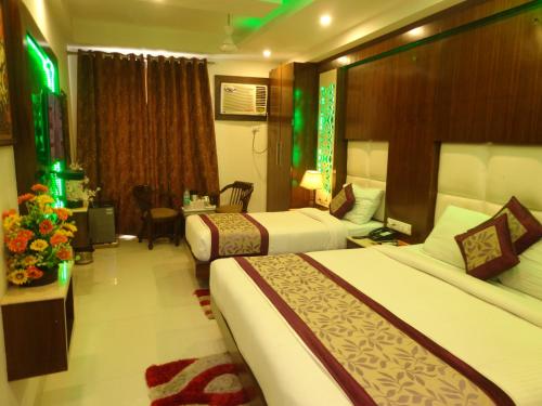 a hotel room with two beds and a desk at Hotel Station View in New Delhi