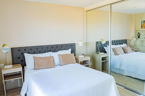 a bedroom with a large white bed and a mirror at Condominio Ibero-Star - Praia do Forte in Praia do Forte