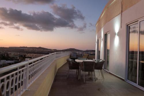 a balcony with a table and chairs on top of a building at PrimeRose Penthouse in Sannat