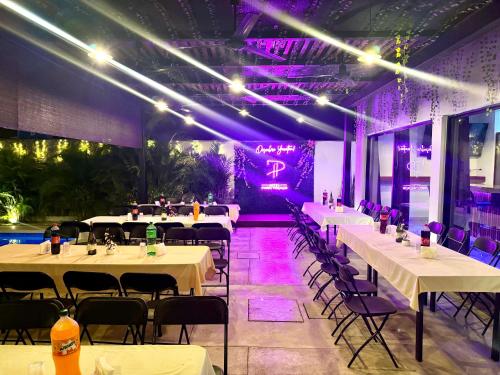 a restaurant with white tables and chairs and purple lighting at Hotel Puerto Tixkokob in Tixkokob