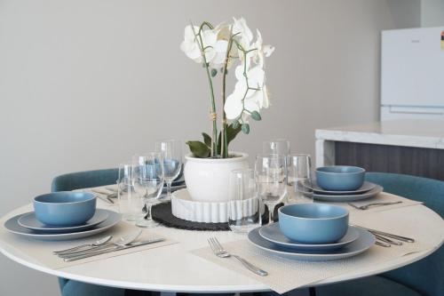 a table with plates and glasses and a vase with flowers at SOP 07 Stylish and Cosy 2 Bedroom Apartment in Sydney