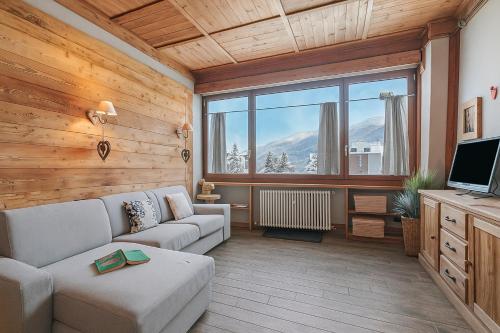 een woonkamer met een bank en een groot raam bij Studio Charming Sportinia - Happy Rentals in Sauze d'Oulx