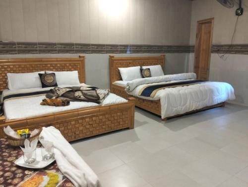 two beds sitting in a room with a table at Neelam Water View Hotel in Kundālshai