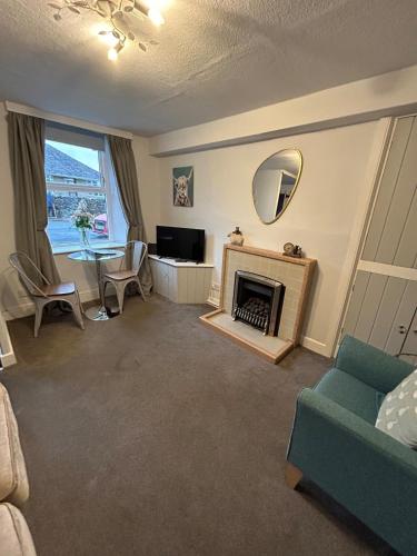 a living room with a fireplace and a television at 1, Bank End Cottages in Ingleton