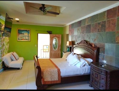 1 dormitorio con paredes verdes, 1 cama y 1 silla en Hotel Gues, en La Guaca