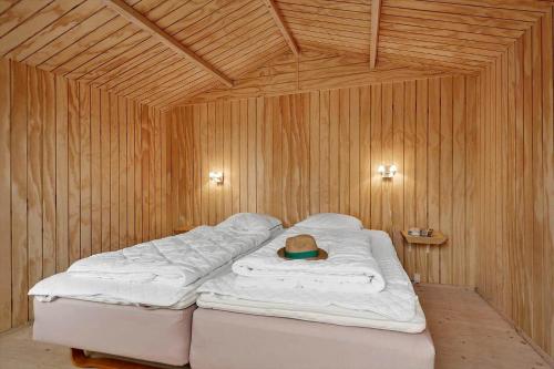 a bed in a wooden room with a hat on it at 30732-Odder-Skovgardsparken-32 in Amstrup