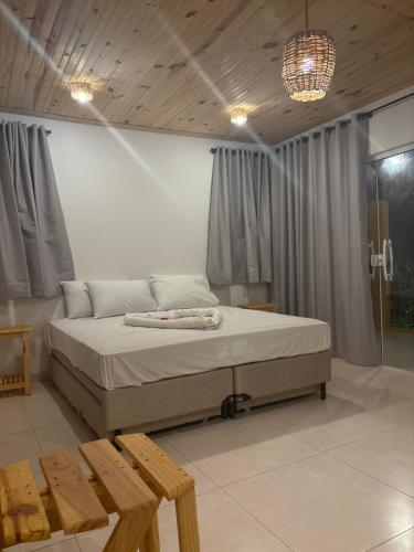 a bedroom with a bed and two wooden benches at Chalé vista mar in São Miguel do Gostoso