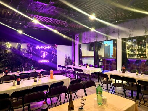 a banquet hall with white tables and chairs and purple lighting at Hotel Puerto Tixkokob in Tixkokob