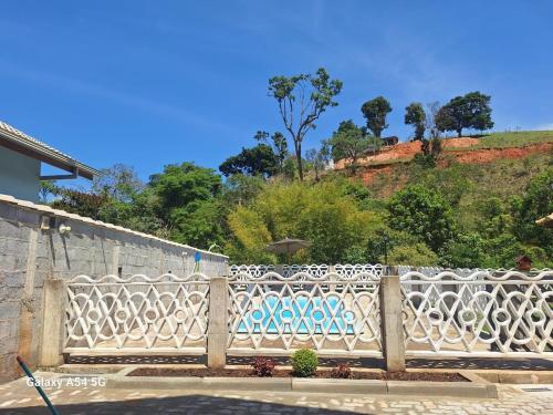 a white fence in front of a hill at Chalé Aconchego in Camanducaia