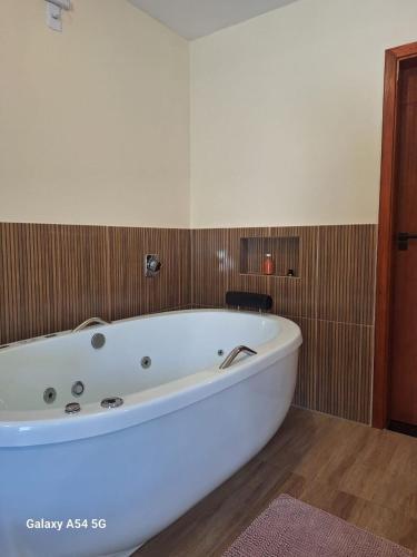 a large white bath tub in a bathroom at Chalé Aconchego in Camanducaia