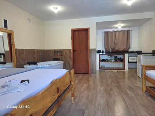 a bedroom with a large bed and a bath tub at Chalé Aconchego in Camanducaia