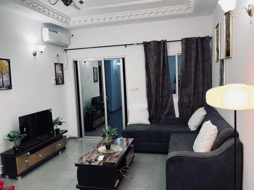 Una sala de estar con un sofá y un televisor en Appartement Brel, en Yaoundé