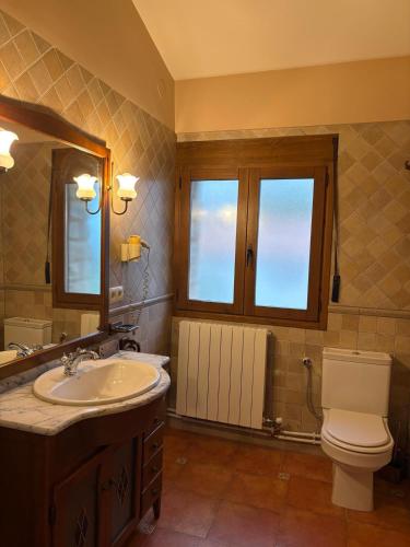 a bathroom with a sink and a toilet and a mirror at Hostal Todolella in Todolella