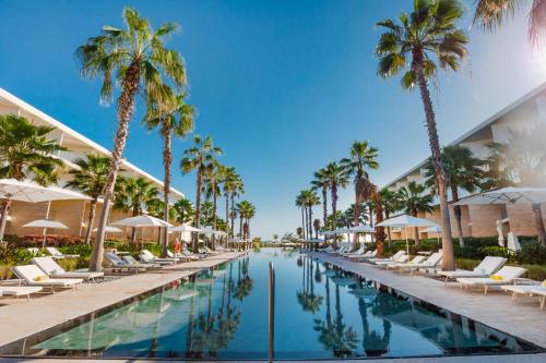 a swimming pool with chairs and palm trees at Family Selection at Grand Palladium Select Costa Mujeres - All Inclusive in Cancún