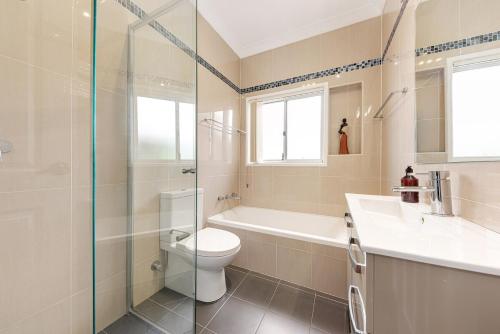a bathroom with a toilet and a sink and a shower at Luxury 3 bedroom 2 bathroom full home with easy access near Cronulla in Lilli Pilli