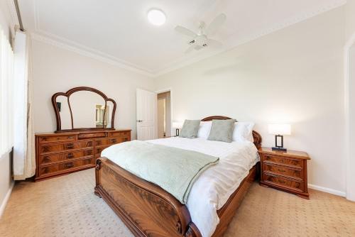 a bedroom with a bed and two dressers and a ceiling fan at Luxury 3 bedroom 2 bathroom full home with easy access near Cronulla in Lilli Pilli