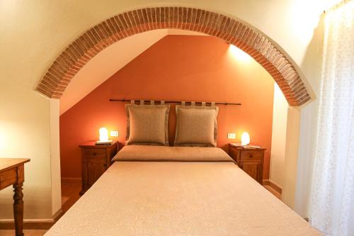 a bedroom with a large bed with an arch above it at SweetHome San Martino in San Gimignano