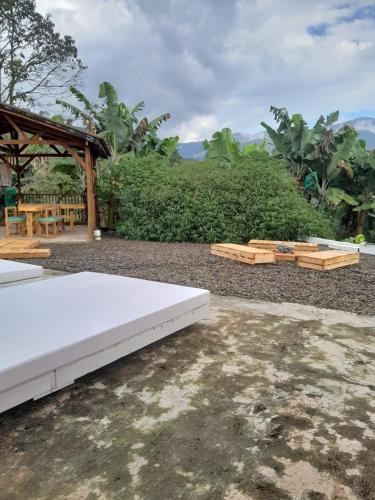 a white bed and wooden benches in a yard at Fresh Start in Jardin