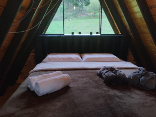 a bed in a room with a window at Chalé do lago in Campo Alegre