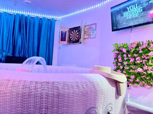 a room with a couch and a tv and flowers at Guest House Paradise Central in Maidstone
