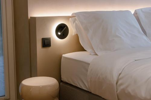 ein Bett mit weißen Laken und ein Hocker neben einem Fenster in der Unterkunft Warm family home by the sea - Villa La Madrague in Oostduinkerke-Bad