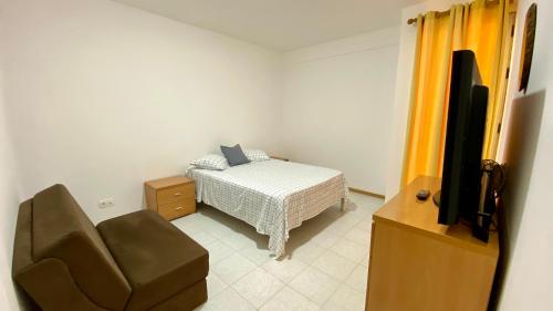 a bedroom with a bed and a tv and a chair at Airport Residence - Vila Acácia I in Praia