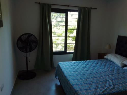 a bedroom with a bed and a window with a fan at Alojamiento El Pucará in San Antonio de Arredondo