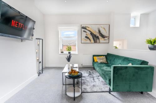 a living room with a green couch and a tv at Modern and Comfy Church Rd Flat 2 with Parking in Newport