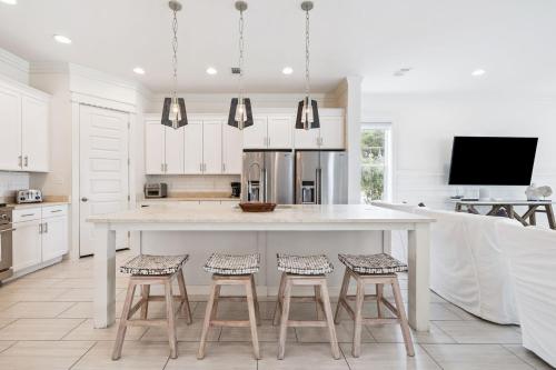 a white kitchen with a large white table and stools at Inlet Beach Reunion House by 30A Escapes in Inlet Beach