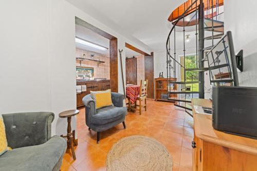 a living room with chairs and a tv and a staircase at Mountain View Cottage in Seixal