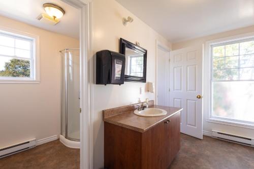 a bathroom with a sink and a tv on the wall at Auberge Zacharie in Rivière-à-Pierre