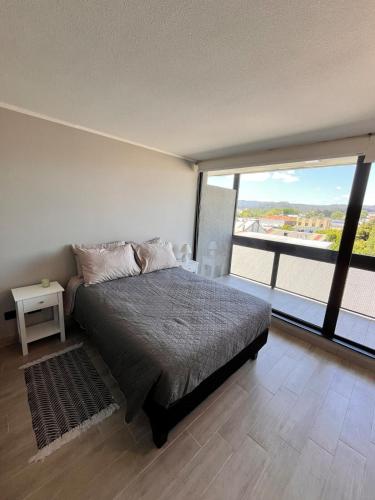 a bedroom with a bed and a large window at Refugio Valdiviano - Tu descanso junto al rio in El Cerrillo