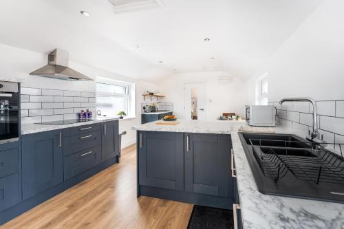 a kitchen with blue cabinets and marble counter tops at Modern and Comfy Church Rd Flat 2 with Parking in Newport