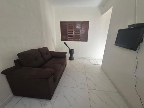 a living room with a brown couch and a television at Barra do Cunhaú - Barra Mar in Canguaretama