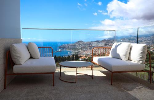 two chairs and a table on a balcony with a view at FLH Funchal Bay View Escape with Pool in São Gonçalo