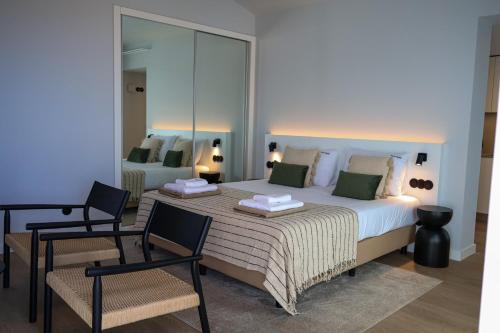 ein Schlafzimmer mit einem großen Bett und zwei Stühlen in der Unterkunft FLH Funchal Studio Blue View Gardens in São Gonçalo