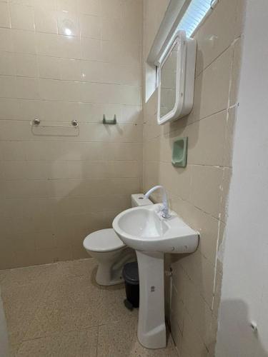 a bathroom with a toilet and a sink and a mirror at Pousada Praça da Bíblia - Santa Maria da Vitória in Santa Maria da Vitória