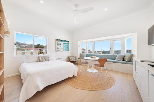 a white bedroom with a bed and a couch at Beachfront 1 Bed across from iconic BONDI BEACH in Sydney