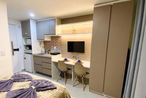 a bedroom with a kitchen and a desk with chairs at Studio Al Mare - Ocean Blue in Porto De Galinhas