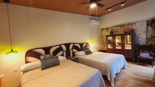a hotel room with two beds and a mirror at Casona Origen Merida in Mérida