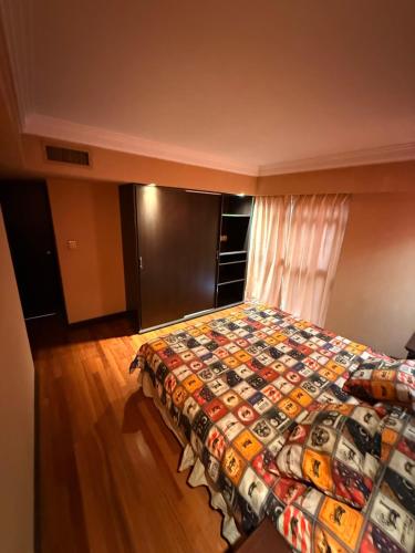 a bedroom with a bed with a colorful quilt at Premium Apart centrico con Sauna, piscina y gimnasio in Mendoza