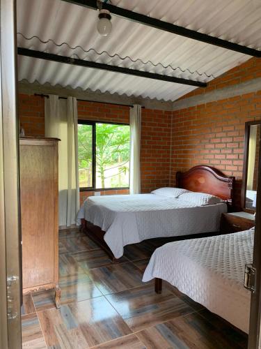 a bedroom with two beds and a brick wall at Villa Pospon in Buga
