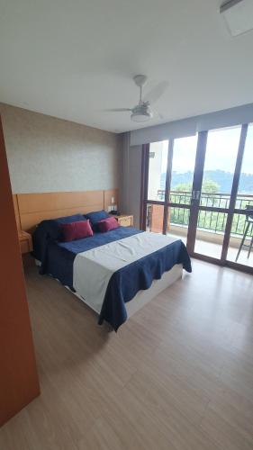 una camera da letto con un letto grande e una grande finestra di Flat lindo em pedra azul a Pedra Azul