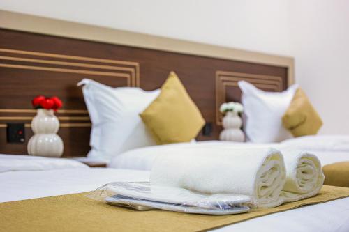 a hotel room with two beds with towels on a tray at فندق بارك الياس in Aţ Ţunḑubāwī