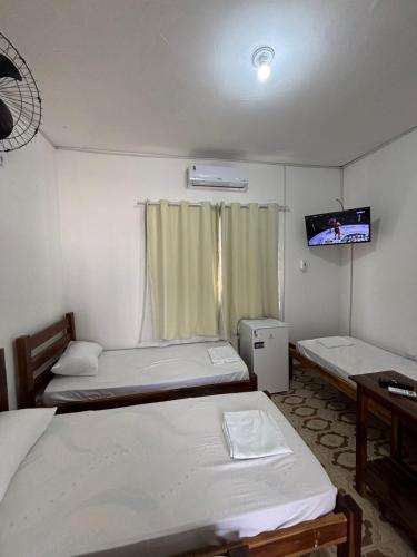 a small room with two beds and a tv at Pousada Praça da Bíblia - Santa Maria da Vitória in Santa Maria da Vitória