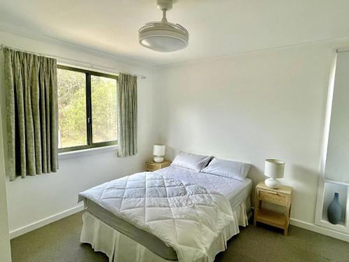 a white bedroom with a bed and a window at Condon 53 in Evergreen
