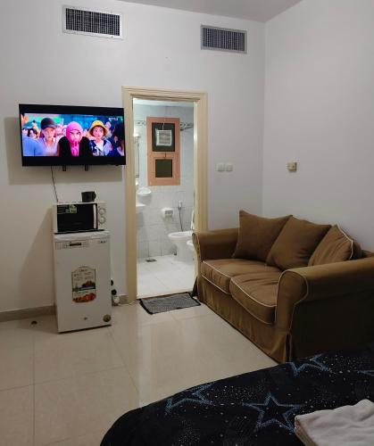 a living room with a couch and a flat screen tv at Room with Private Bathroom in Abu Dhabi
